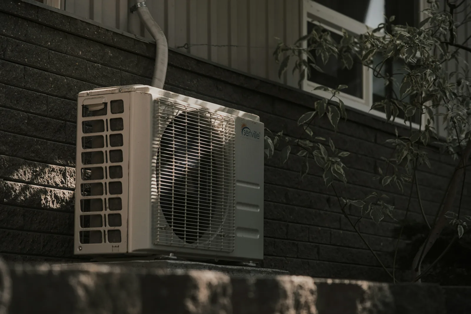 Outdoor ductless mini-split condenser installed beside an existing home